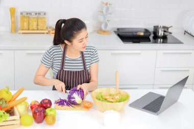 Mutfakta yemek yapmak için tablet bilgisayar kullanan bir kadın.
