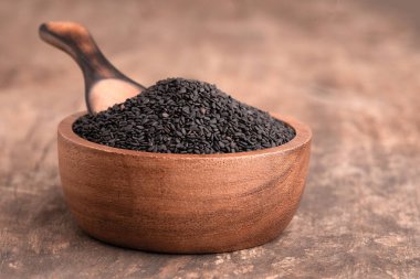 Siyah Susam, ahşap arka planda yakın çekim. Tahta kaşıkta siyah masada susam tohumu.