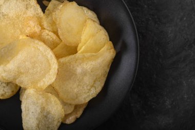 Altın dalgalı patates cipsleri yemek arkaplanı için yakın plan. Siyah arka planda patates cipsi.