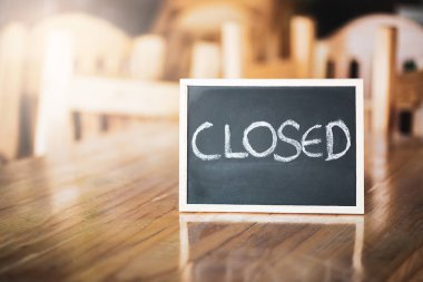 Kapalı. Ahşap bir masaya yerleştirilmiş Mockup çerçevesinde kapalı bir levhaya yakın çekim..