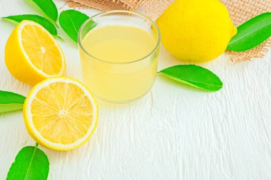 Küçük bir kasede taze sıkılmış limon suyu ahşap masa üzerindeki limon yığını yiyecek ve içecek kavramları, sağlık vitaminleri.