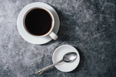 Kahve, beyaz fincan ve kahve çekirdekleri, siyah taş arka plan, üst manzara.