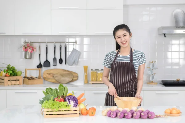 Woman cooking in the kitchen, Asian women cook with vegetables, clean white kitchen.