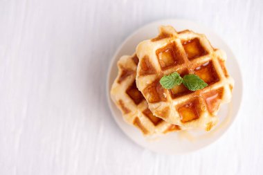 Beyaz ahşap bir masanın üzerine ballı kepekli waffle. Beyaz ahşap bir masada waffle