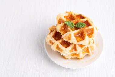 Beyaz ahşap bir masanın üzerine ballı kepekli waffle. Beyaz ahşap bir masada waffle