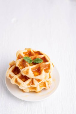 Beyaz ahşap bir masanın üzerine ballı kepekli waffle. Beyaz ahşap bir masada waffle
