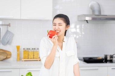 Mutfakta kırmızı dolma biber tutan bir kadın.