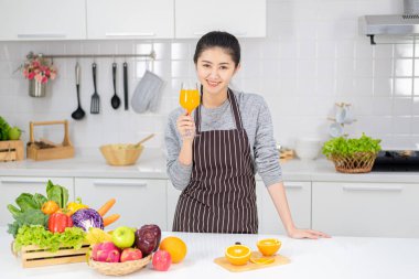 Güzel genç bayan mutfakta taze portakal suyu içiyor. Sağlıklı beslenme