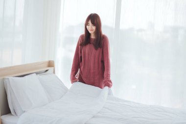 Kadınlar odadaki yatağa çarşaf sererler..