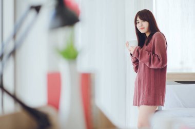 Beyaz bir odada, yatağın üzerinde kahve, çay, süt içen bir kadın (kahve, çay, süt))