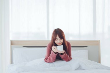 Beyaz bir odada, yatağın üzerinde kahve, çay, süt içen bir kadın (kahve, çay, süt))