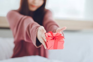 Kadın hediyeye bakarken şaşırdı. Genç bir kadın, erkek arkadaşından sürpriz bir hediye kutusu alıyor..