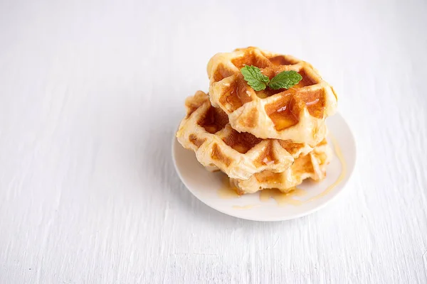 Beyaz ahşap bir masanın üzerine ballı kepekli waffle. Beyaz ahşap bir masada waffle