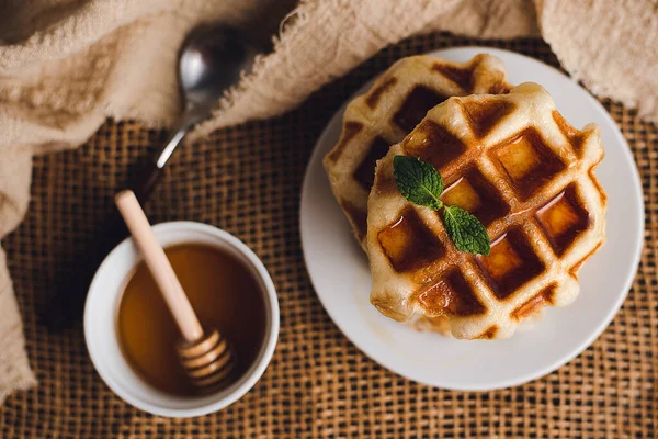 Whole wheat waffles with honey, waffles on a wooden table with honey as an ingredient.