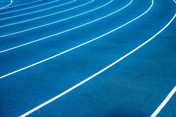 Blue running treadmill track with lane numbers in stadium outdoors.Starting grid of race track at the stadium