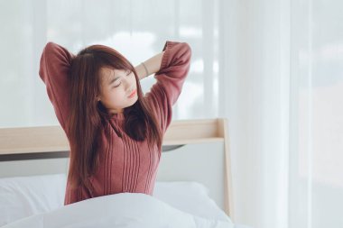 Sabahları kollarını gererek uyanan bir kadın. Mutlu bir kadın sabah yatağında uyanıyor..