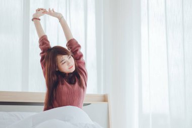 Sabahları kollarını gererek uyanan bir kadın. Mutlu bir kadın sabah yatağında uyanıyor..