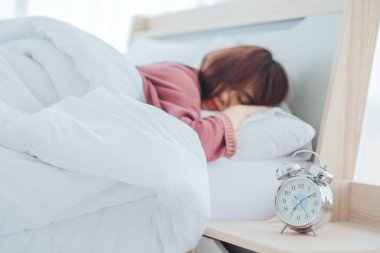 Sabah vaktinde uyanmak, komodinin başında duran çalar saat sabahın erken saatlerinde arka planda uyuyan bir kadını uyandırmak için çalacak.