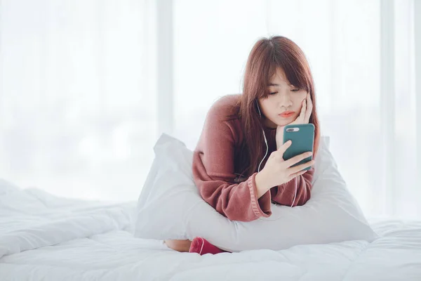 A woman playing on the phone in the bed in the house