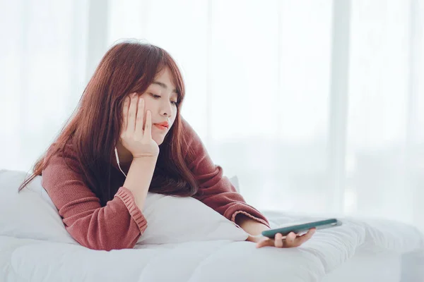 A woman playing on the phone in the bed in the house