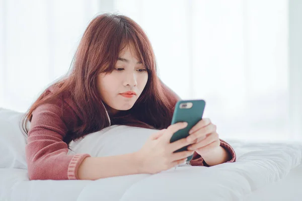 A woman playing on the phone in the bed in the house