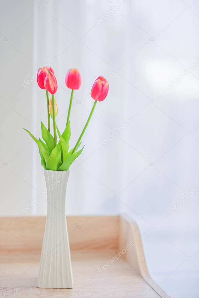 Close up of modern bed and bedside cabinet with clock and flower vase in the bedroom,bedroom. bouquet on the nightstand