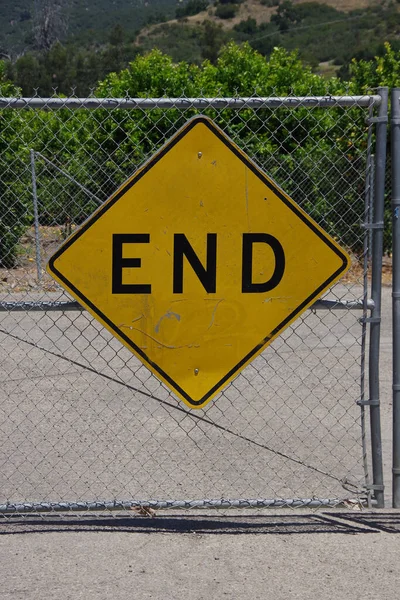 A large yellow traffic sign END on a gate marking the end of a public road