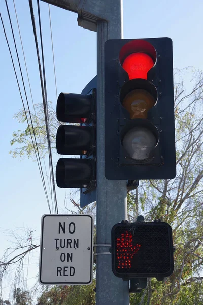 Close-up view of a traffic signal at an intersection showing red lights for vehicles and pedestrians and a NO TURN ON RED sign