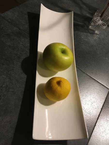 新鮮なリンゴと新鮮なレモンの側面をホームキッチンカウンターの細長い磁器のボウルに並べて表示します — ストック写真