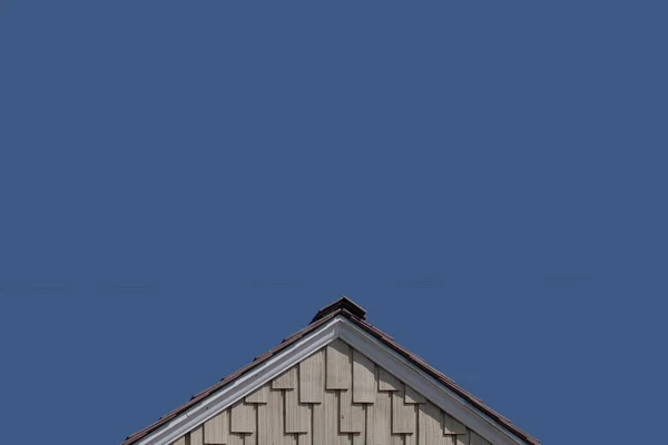 青い空の下で尖った屋根の先端を持つ木製の帯状のファサードの低角度部分ビュー — ストック写真
