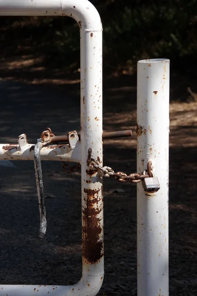 Close-up view of public park gate locked with a chain and a padlock