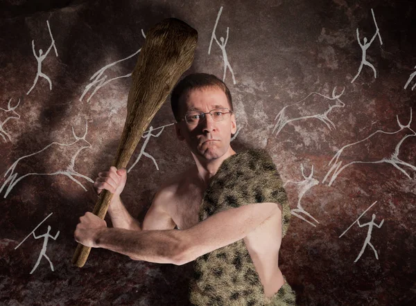 A man in glasses and in primitive skin with a cudgel in his hands threatens. The metaphor of political threats of the modern world