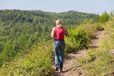 Bir sırt çantası ile bir kadın turist bir orman yolu yürüyüş