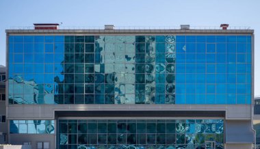 Mimari ve mavi gökyüzü dikdörtgen bir binanın cam duvarına yansıyor. Modern geometrik mimari ve kentleşme teması