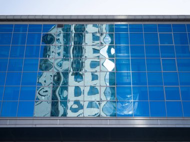 Bozuk mimari, ofis binasının mavi cam duvarına yansıyor. Modern geometrik mimari ve kentleşme teması