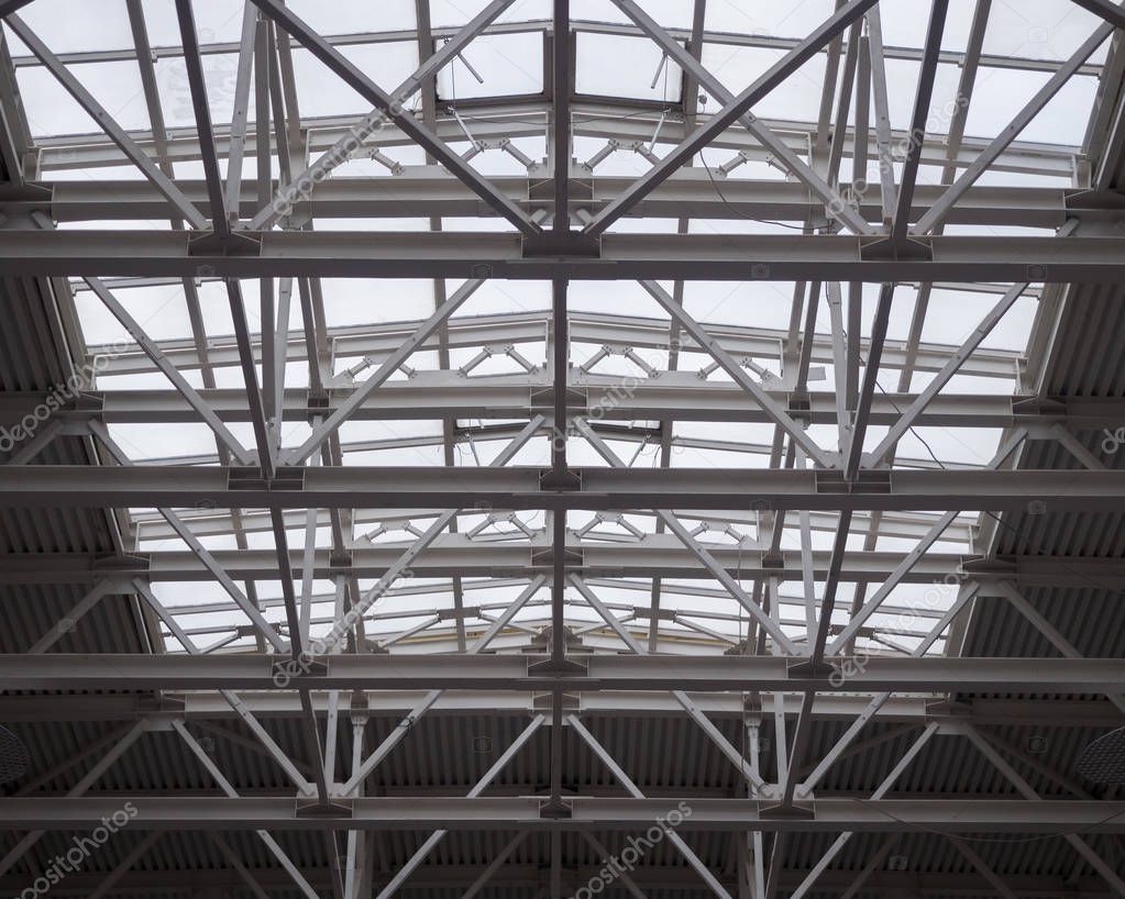 Openwork metal trusses of a huge roof in a hypermarket. Theme of modern opportunities for the construction of public facilities