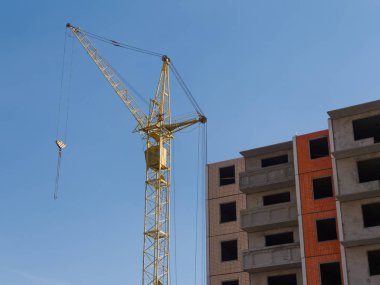 Çalışan bir vinç ve gökyüzüne karşı inşaat halindeki bir evin bir parçası. İnşaat halindeki gelişmekte olan bir konut piyasasının teması