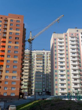 İnşaat vinci tuğla ve panel evler arasında çalışır. İnşaat halindeki gelişmekte olan bir konut piyasasının teması
