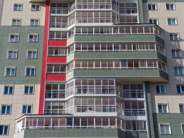 Fragment of the new colored facade of the house with loggias. The theme of an emerging housing market under construction