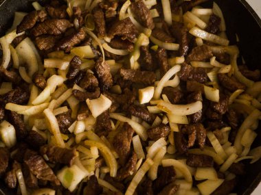 Soğanlı et bir tavada kızartılır. Sığır stroganoff pişirme. Yakın plan.