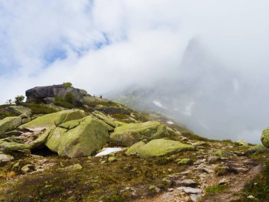 Sert dağ manzarası. Kayalarda sis var. Yaz bulutlu günü