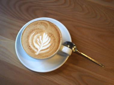 Ahşap bir yüzeyde bir fincan latte. Güzel krema çizimi