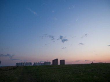 Bozkırdaki yeni evlerin üzerinde büyük, güzel bir günbatımı gökyüzü. Modern şehirlerin gelişimi