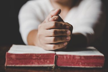 Karanlık bir İncil ile ahşap masa üzerinde dua eller kadın