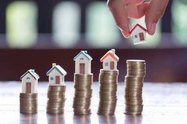 Arka plan olarak hesap makinesiyle ev modeli ve paralar yığın. Konsept Emlak merdiven, ipotek ve gayrimenkul yatırım için.