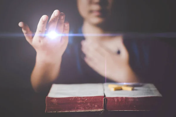 Woman praying on holy bible in the morning. Teenager woman hand with Cross and Bible praying, Hands folded in prayer on a Holy Bible in church concept for faith, spirituality and religion.