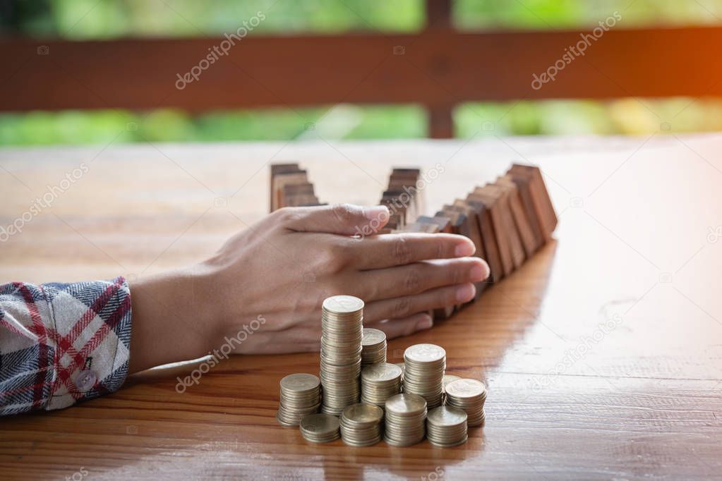 Businesswoman stops the domino effect from risking financial investment, concept image of investing and banking.