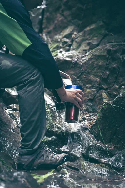 Man taking water from mountain spring on hiking trip