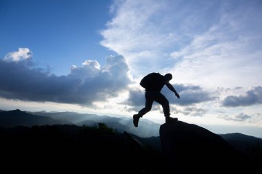 Günbatımında iki Kayalık Dağları arasındaki uçurumun atlama adam. özgürlük, risk, sorun ve başarı.