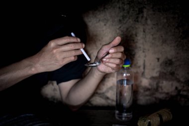 Adam yapar eroin eroin almaya hazırlanıyor, içine bir kaşık eroin dökülen. Suç ve uyuşturucu bağımlılığı kavramı.